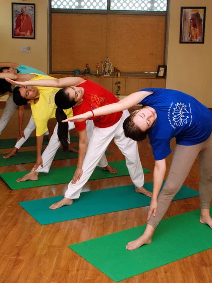 A group of students in a weekend beginner class practices Trikonasana (Triangle Pose) in unison, demonstrating the focused and harmonious energy of our sessions.