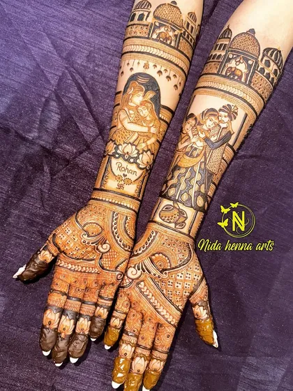 A complete bridal mehandi telling multiple stories. This design combines a beautiful portrait of Shiva and Parvati, a family portrait, and architectural elements, all flowing together from the hands to the arms.