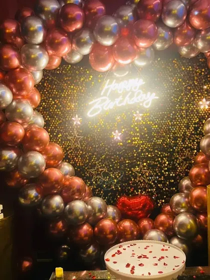 A stunning view of a birthday setup ready for the cake cutting. The heart-shaped balloon arch and romantic props make it perfect for celebrating with a loved one.