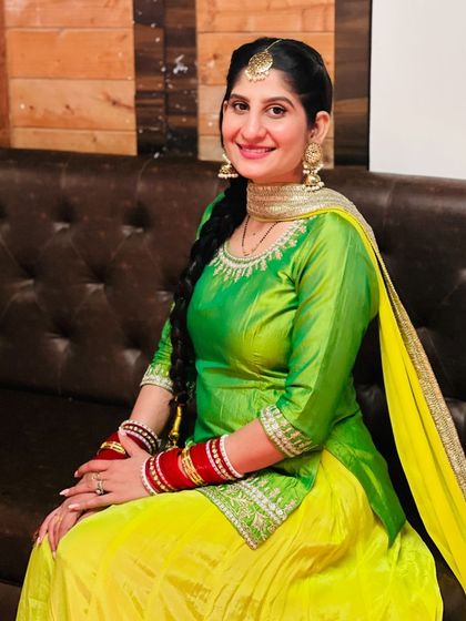 A happy client in a vibrant green and yellow Punjabi suit, perfect for a Mehendi or Haldi function. The traditional bangles complete the look.