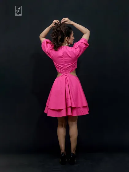 A rear view of the pink dress, highlighting the interesting back cut-out and the structure of the tiered skirt.