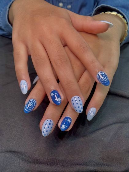 A playful, celestial-themed set with hand-painted stars, swirls, and polka dots in shades of blue. Each nail tells a little part of a starry night story.