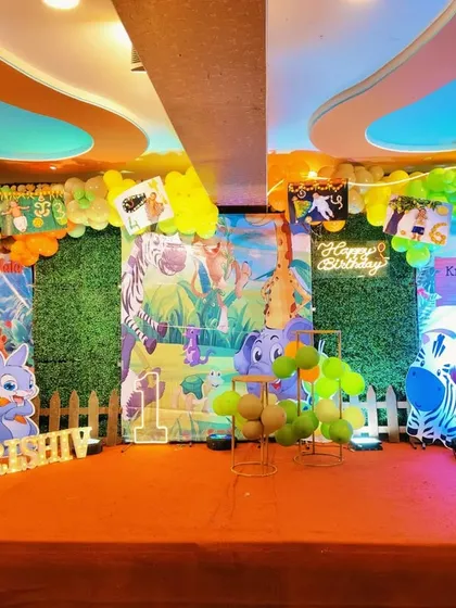 We create a complete stage look for your child's wild one birthday. This jungle theme includes a lush green grass backdrop, colorful balloon garlands, and multiple animal character cutouts to set the scene.