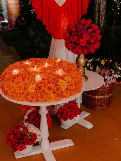 A beautiful centerpiece made of a dense arrangement of orange marigolds with candles nestled within, creating a warm and traditional focal point.