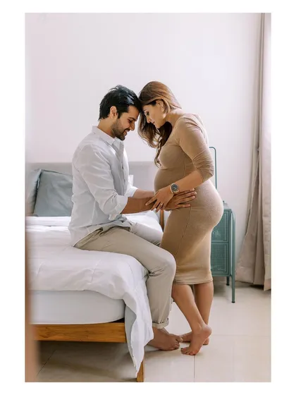A tender moment where the couple connects, forehead to forehead, by the bed. This pose feels so natural and intimate, perfectly capturing the love that started their family.