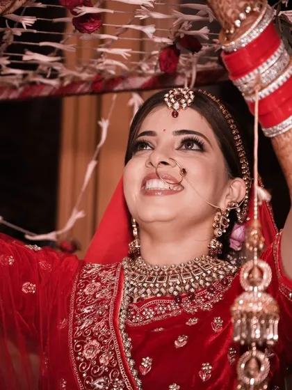 A happy bride during her 'phoolon ki chaadar' entry, looking up with a beautiful smile, full of hope and joy.