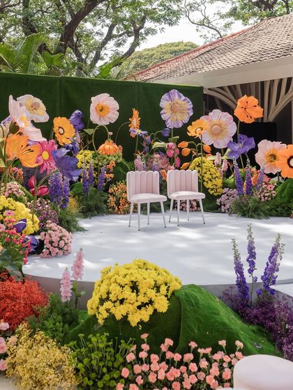 The ceremony stage, where two simple chairs are set amidst a spectacular, amphitheater-like arrangement of colorful flowers.