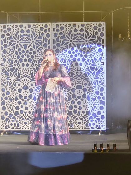 On the grand stage, addressing the audience. My job is to be the bridge between the performances on stage and the energy of the crowd, keeping everyone hooked.