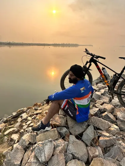 A cyclist enjoying a moment of solitude by the water at sunrise. These are the peaceful moments that make early morning rides so special.