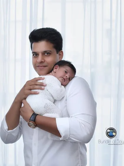A father's gentle hold. This portrait focuses on the quiet, strong bond between a dad and his new baby, a memory he will always cherish.