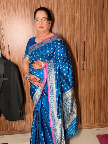 A full-length shot of the mother in her beautiful blue Banarasi saree, looking poised and graceful.