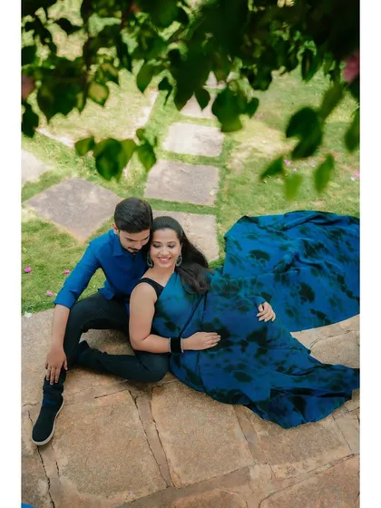 A romantic overhead shot of the couple relaxing in a beautiful garden setting. The framing through the leaves adds a sense of intimacy and privacy to the moment.