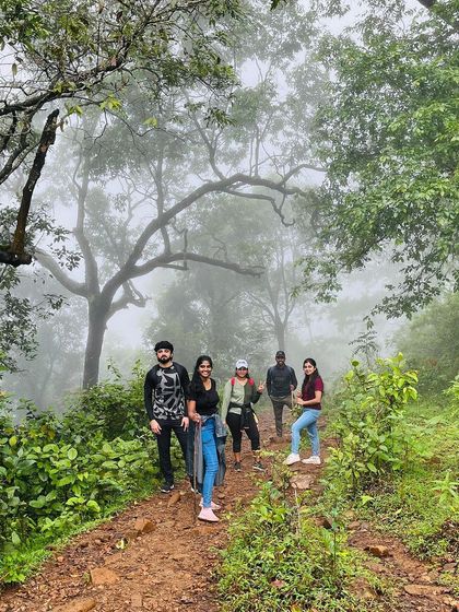 A group of friends posing in a misty forest trail during the Netravathi trek. The atmosphere is truly magical.