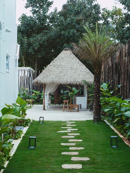 A stone pathway leads through a manicured lawn to the tranquil gazebo. This view showcases the thoughtful landscape design that integrates the built structures with the natural environment.