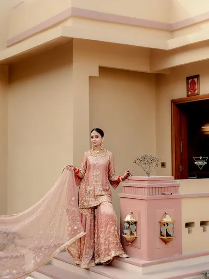 The bride in her stunning pink sharara, her flowing dupatta adding a touch of drama and elegance to this beautiful portrait.