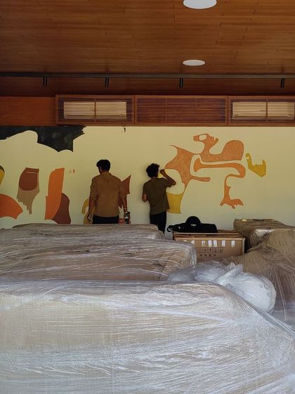 An early stage of a mural, with the initial shapes blocked out on the wall amidst a busy work site.
