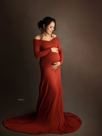 A classic and timeless maternity portrait. The mom-to-be cradles her bump in a simple, elegant burnt-orange gown.