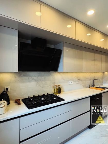 A wide view of the handle-less cabinetry and integrated appliances in this modern kitchen. The under-cabinet lighting strip runs the length of the counter, ensuring a well-lit workspace and highlighting the marble-effect backsplash.