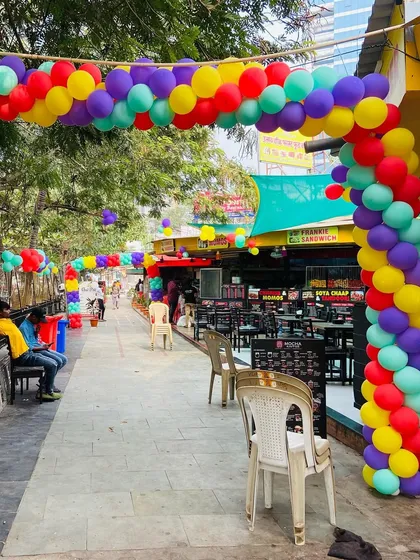 A long walkway at an outdoor venue decorated with a vibrant, multi-colored balloon arch.