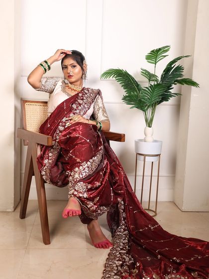 A full-length seated pose showcasing the entire bridal outfit, from the hairstyle to the alta on the feet.