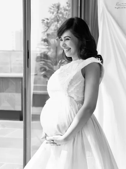 The pure joy of a mother-to-be, captured in a bright, airy black and white style. The natural light from the window gives her an incredible glow.