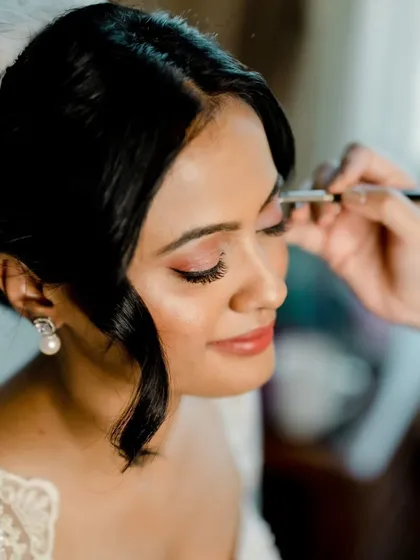 Behind-the-scenes moments from a beautiful Goa wedding. These shots show the careful process of creating the perfect winged liner and soft blush, ensuring the bride feels her best.