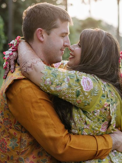 A tender hug between the couple, both adorned with floral jewelry, capturing the love and warmth of their Haldi ceremony.