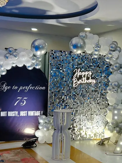 We celebrate life's biggest milestones with style and sophistication. This elegant 75th birthday setup features a dazzling silver sequin wall, a custom neon sign, and large marquee numbers, creating the perfect glamorous backdrop for photos.