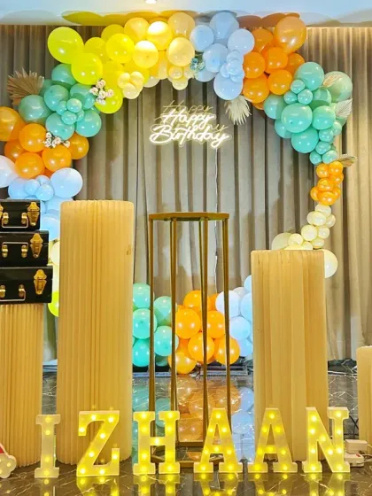 A colorful and friendly dinosaur-themed 6th birthday. This setup includes cute dinosaur cutouts, a vibrant balloon hoop, and marquee letters spelling out the birthday boy's name.