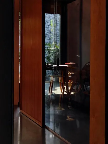 A reflection in the glass captures the quiet, contemplative atmosphere of our studio. The interplay of space, shadows, and silence is central to our design philosophy.