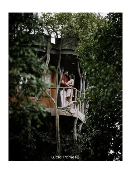 A couple finds shelter and intimacy on a treehouse balcony during a light rain. These unscripted moments often make for the most memorable and romantic photographs.
