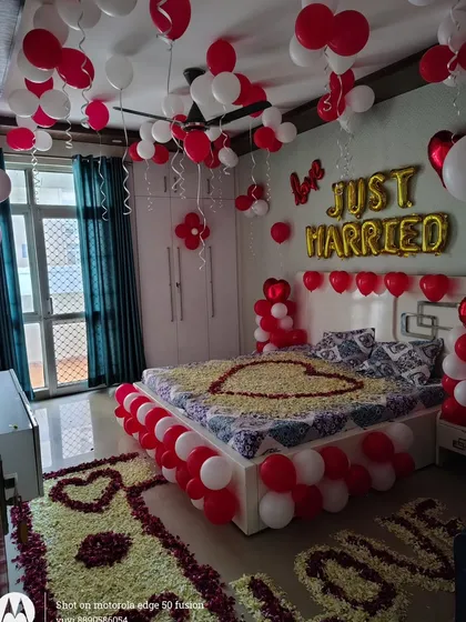 This is a very detailed first night decoration I did in a client's home. The setup includes 'Just Married' balloons, rose petal hearts on the bed and floor, and a border of red and white balloons around the bed.