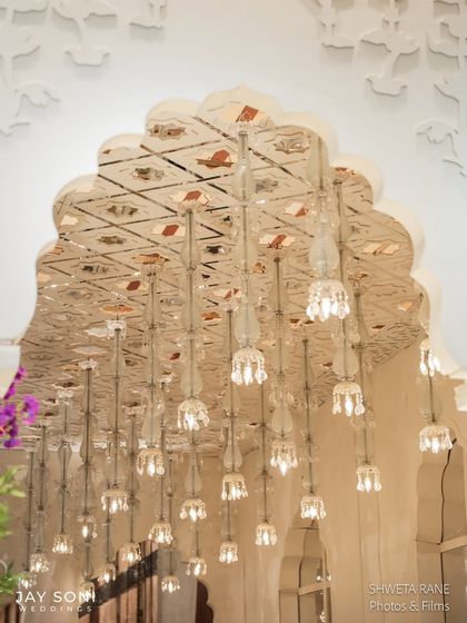A close-up of the stunning lighting detail from the "Garden of Vows" wedding. The hanging crystal lights within the architectural arches added a touch of glamour and sparkle to the floral-filled space.
