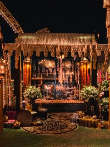 A cozy and opulent seating area from an Arabian Nights cocktail soiree. The canopied structure is adorned with intricate details, traditional lanterns, and plush seating, creating an intimate space for guests.