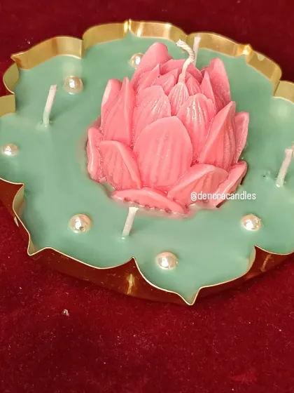 A different angle of the pink lotus urli candle, showing the detail on the petals and the placement of the surrounding wicks.