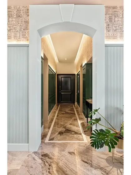 A full view of the arched entrance into the green foyer. The combination of the marble arch, fluted side panels, and architectural wallpaper creates layers of texture and grandeur.