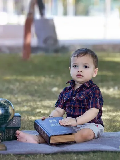 A one-year-old explorer surrounded by books, a globe, and a telescope.