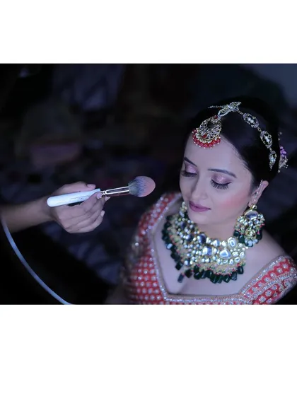 A little behind the scenes magic. Here, I'm applying the finishing touches with a setting powder to ensure the makeup is perfect and long lasting. I use a ring light to see every detail, ensuring a flawless finish.