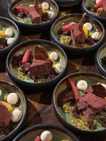 A deconstructed chocolate mousse dessert with passionfruit coulis and meringue drops. This dish is a complex combination of textures and flavours, from rich and creamy to tart and crunchy.