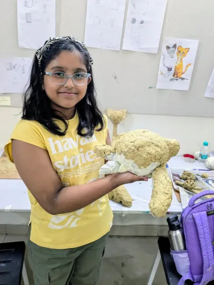 A student proudly holds up her papermache teddy bear before the painting process begins. Building the form is the first and most important step in 3D sculpture.