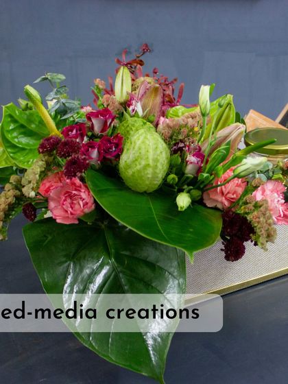 This mixed-media creation, combining fresh flowers with fruits and other gift items, is a growing trend. It's a creative way to design a truly unique hamper.