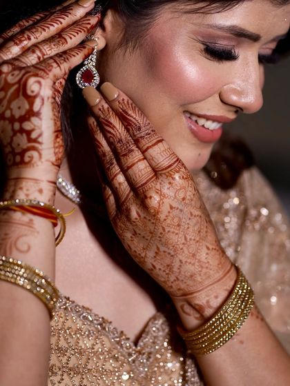 A close-up on the details. This shot highlights the beautiful mehndi and the soft, glowing makeup that makes the bride's smile even brighter.