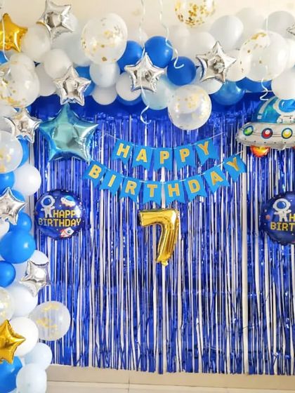 A Doraemon and outer space theme for a 7th birthday. The blue and white balloon arch is accented with star balloons and a spaceship foil balloon.