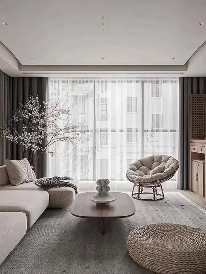 This wide view of a modern living room showcases the importance of natural light in our designs. The floor-to-ceiling windows, sheer curtains, and light color palette create a bright and airy space, perfect for relaxation.