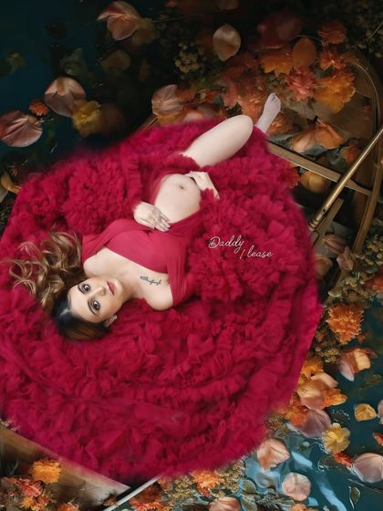 An artistic overhead shot of an expectant mother in a red gown, surrounded by autumn leaves. This setup creates a rich, painterly effect for a one-of-a-kind maternity portrait.