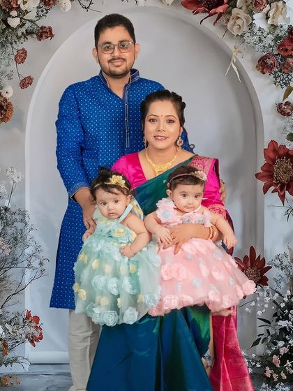 A beautiful family portrait with their twin baby girls. The floral arch provides a stunning backdrop, and coordinating outfits bring the whole image together perfectly.
