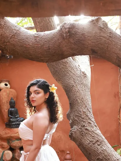 A beautiful portrait framed by the natural curves of a tree. This shot from the Apsara series has a soft, dreamy quality, enhanced by the flower in the model's hair.
