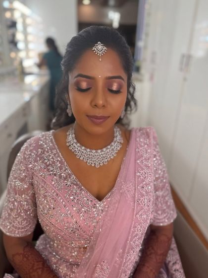 Surya with her eyes closed, showcasing the beautiful pink and gold eyeshadow. This look is perfect for a romantic and modern reception.