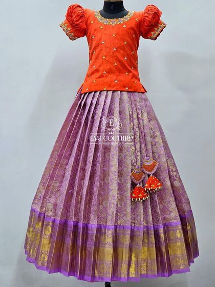 A bright and festive orange and purple Kanchi Pattu lehenga. The blouse has a keyhole back and beautiful tassels.