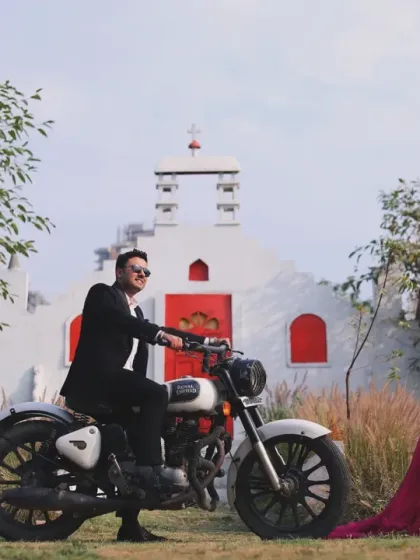 A stylish and unique outdoor shoot at a location with distinct architecture, featuring a couple posing with a classic motorcycle for a cool, modern vibe.